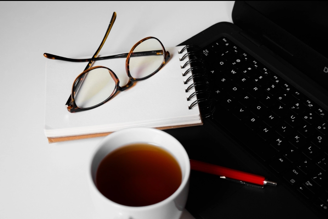 laptop z notatnikiem, okularami i herbatą - widok z góry
