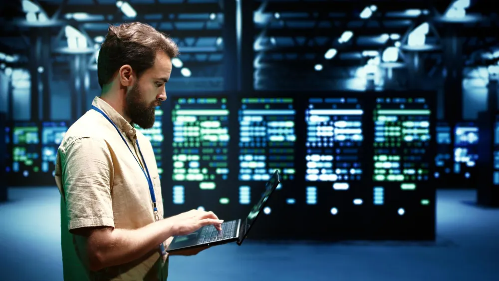 pan z laptopem na tle serwerowni